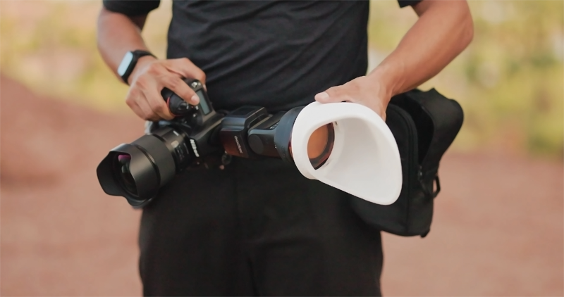 Photographer putting MagBounce 2 reflector on a round-headed hot shoe flash during an outdoor photoshoot