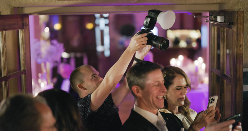 Fotograf ślubny robiąca zdjęcia z lampą błyskową i dyfuzorem MagMod MagSphere 2podczas wesela
